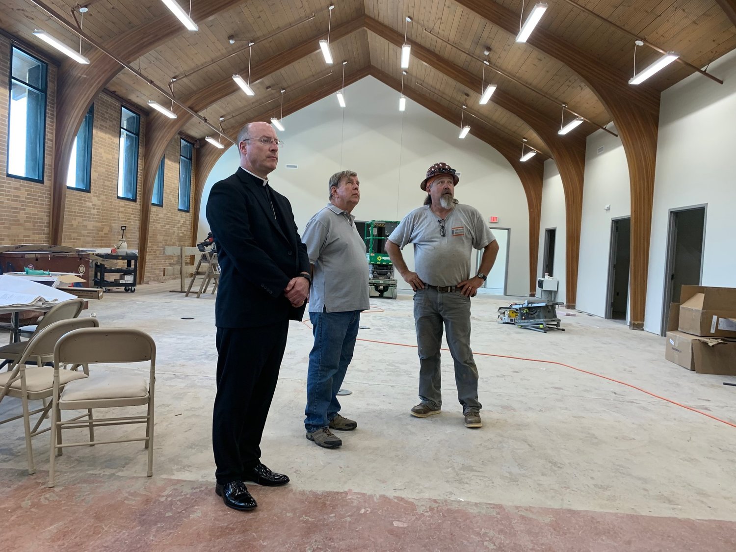 Bishop McKnight, CCCNMO Board Member Jim Wisch, and a construction worker survey the large open room in the middle of the new center.